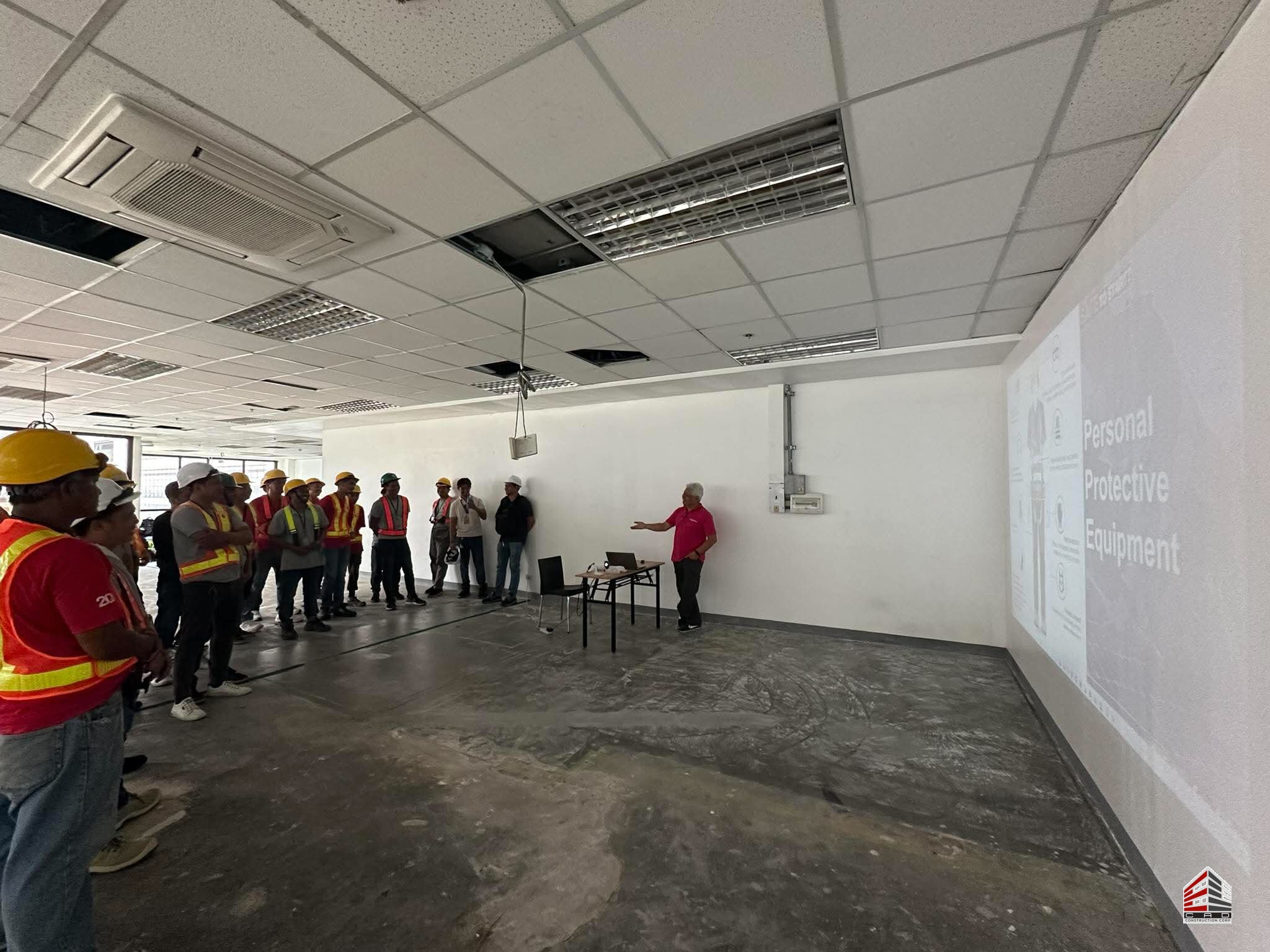 An orientation session inside the 600sqm BGC office space where a presenter uses a projector to display information about Personal Protective Equipment (PPE).